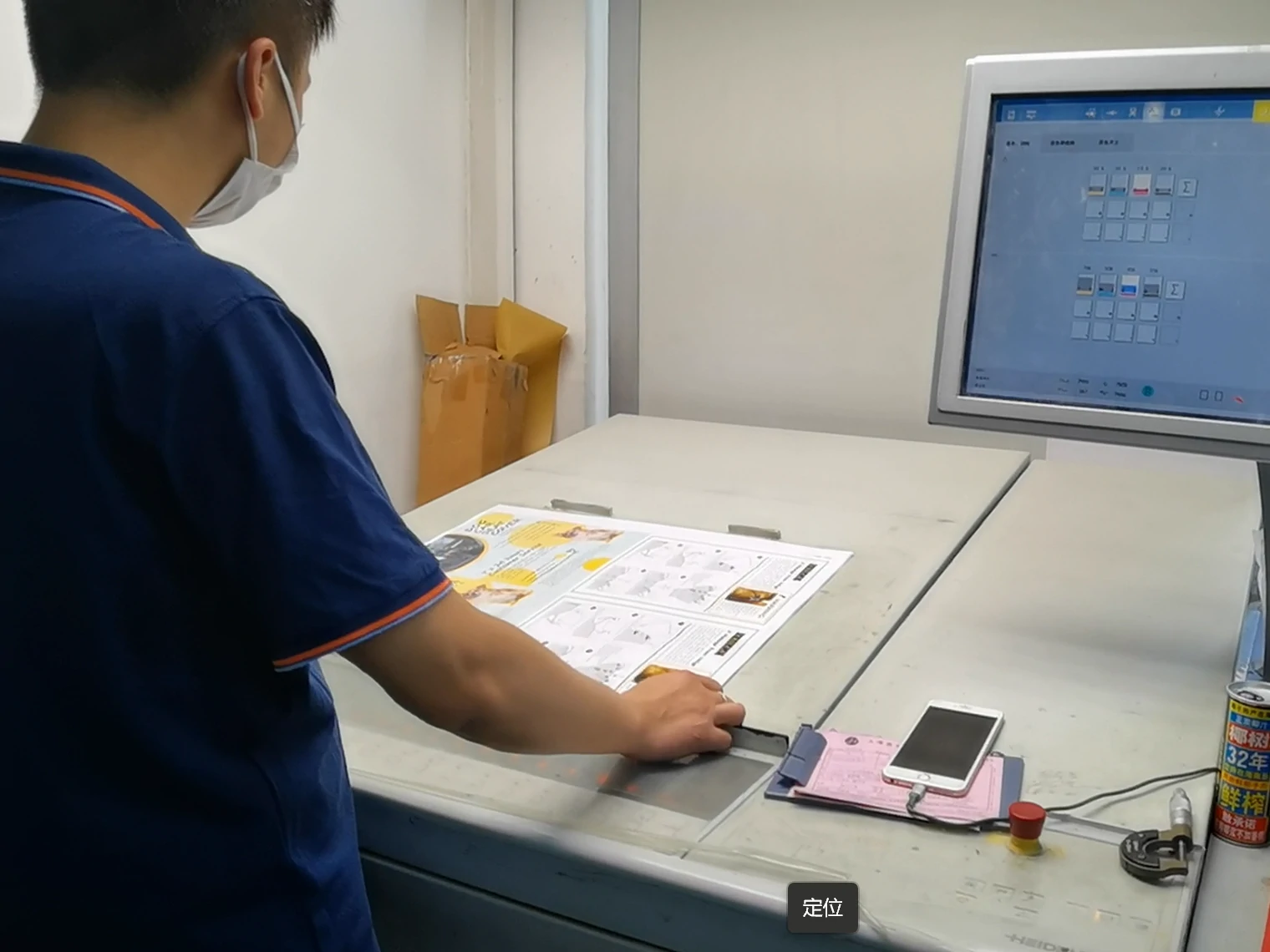 An operator checking a printed sheet at the press console, with the control screen alongside An operator checking a printed sheet at the press console, with the control screen alongside