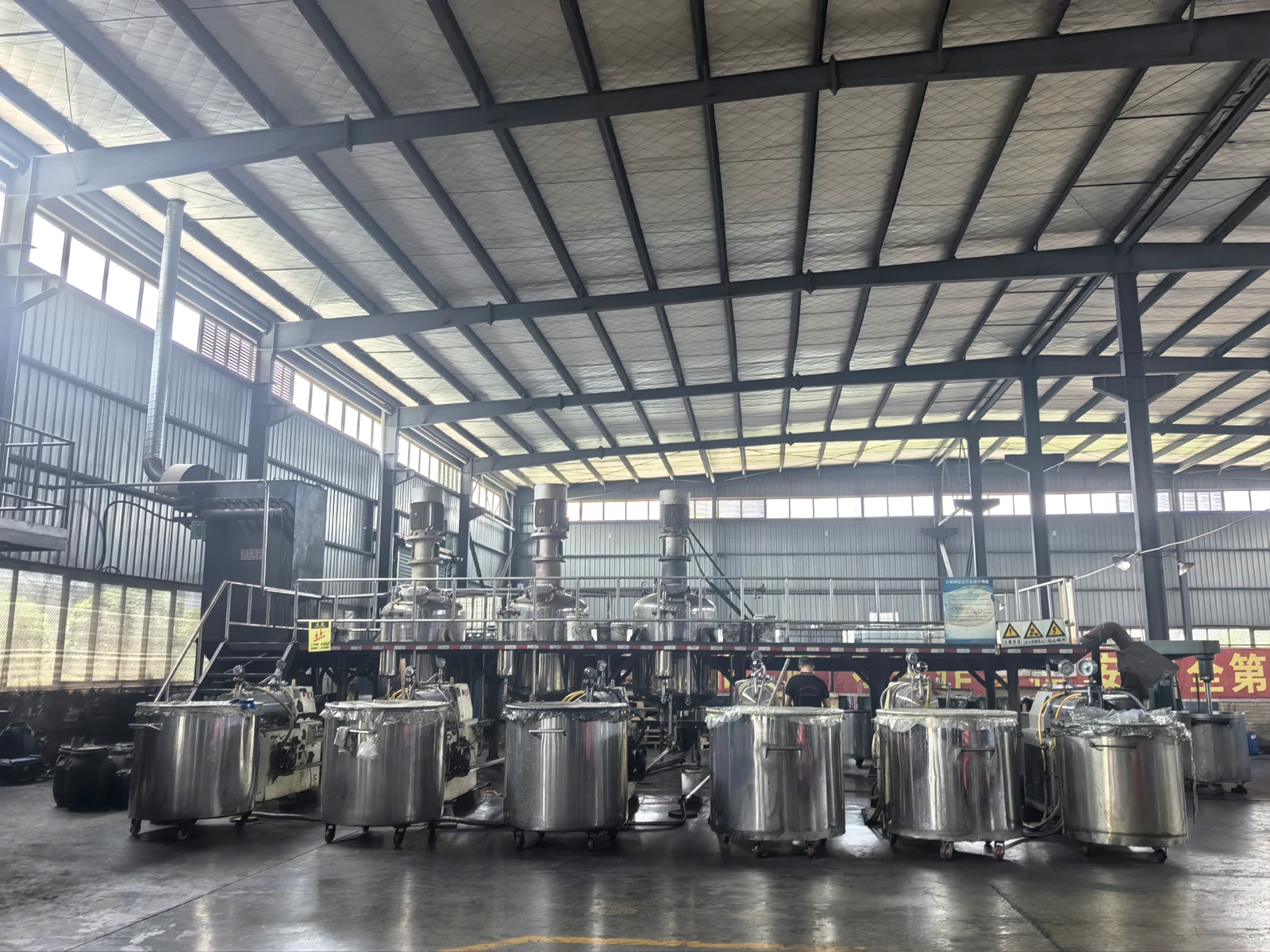 Stainless steel mixing vessels in the PrintBar production hall, with mobile tanks in the foreground Stainless steel mixing vessels in the PrintBar production hall, with mobile tanks in the foreground