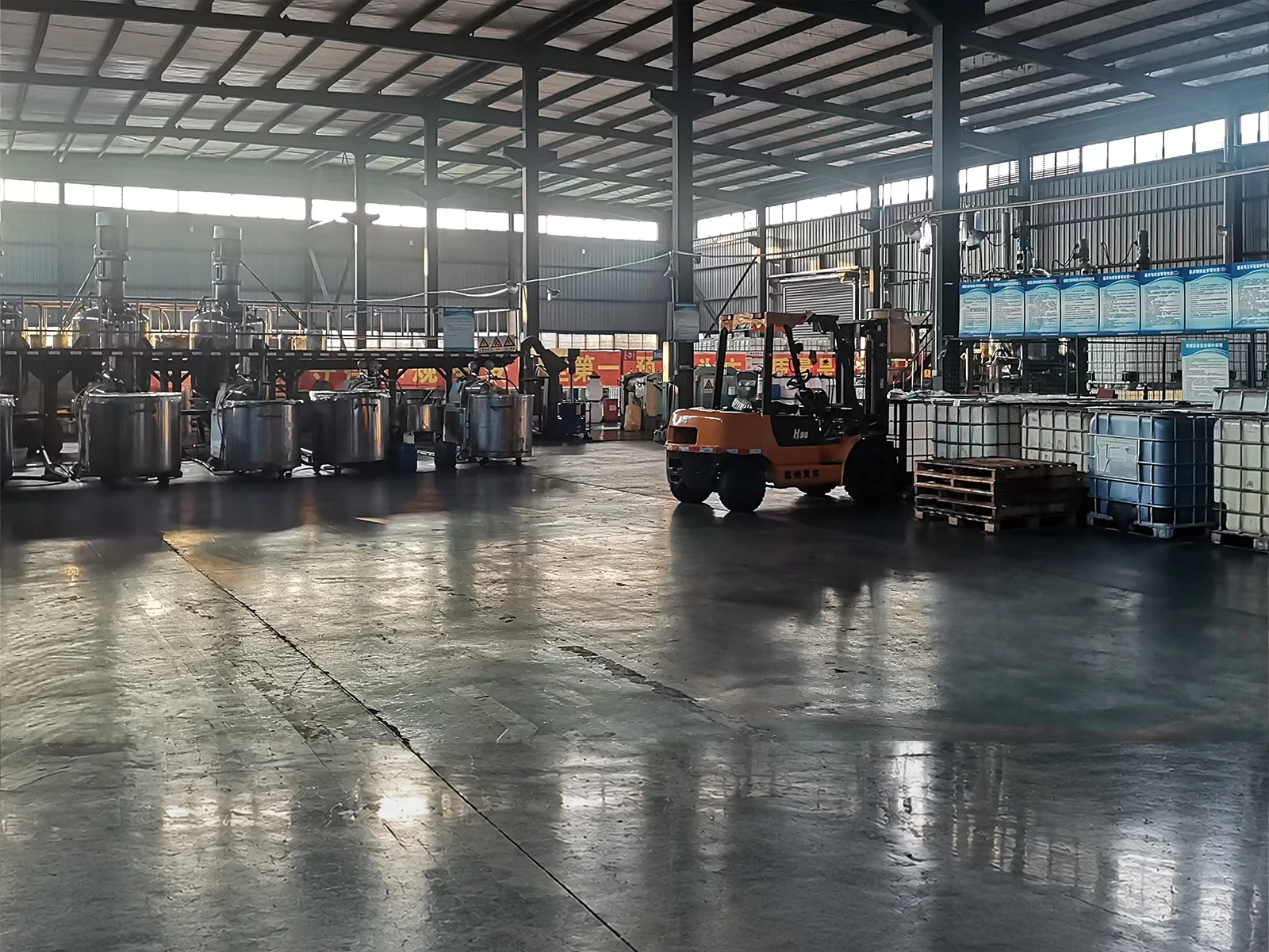 A forklift crossing the PrintBar plant floor, with pallets, IBC totes and mixing vessels alongside A forklift crossing the PrintBar plant floor, with pallets, IBC totes and mixing vessels alongside