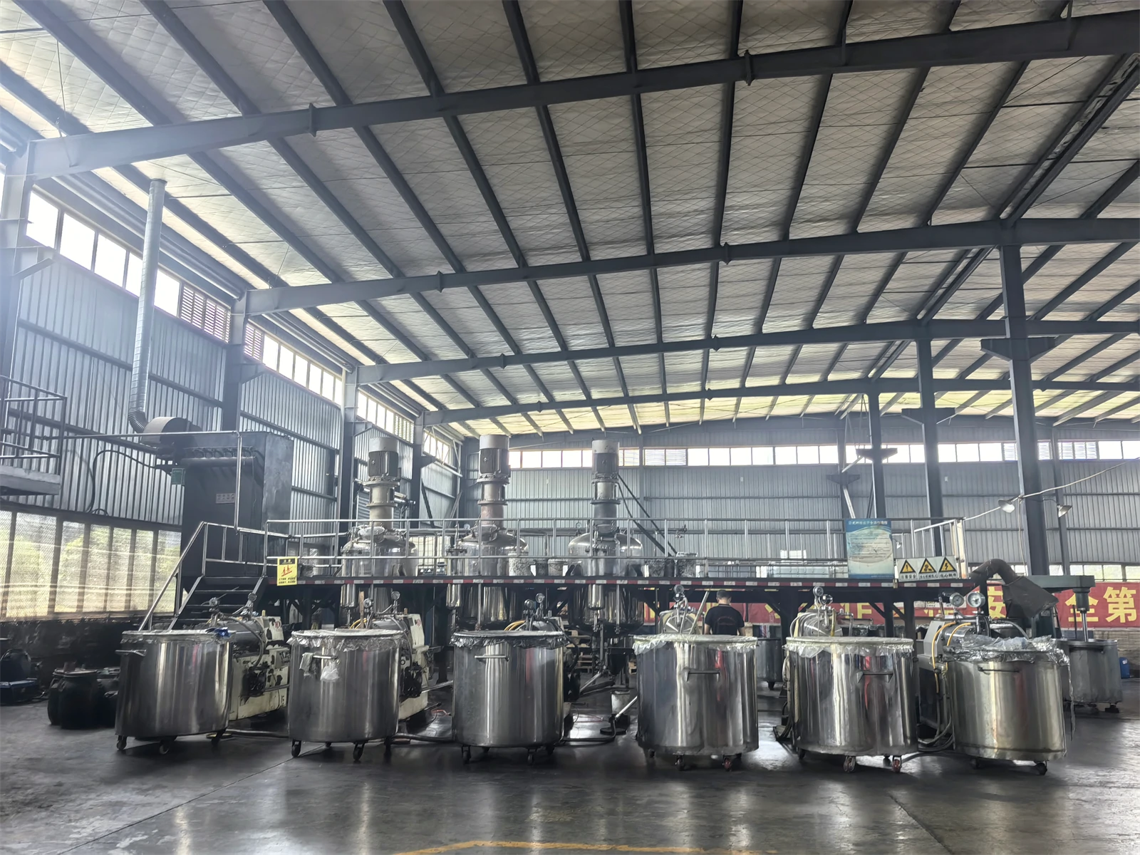 Stainless steel mixing vessels in the PrintBar production hall, with mobile tanks in the foreground Stainless steel mixing vessels in the PrintBar production hall, with mobile tanks in the foreground
