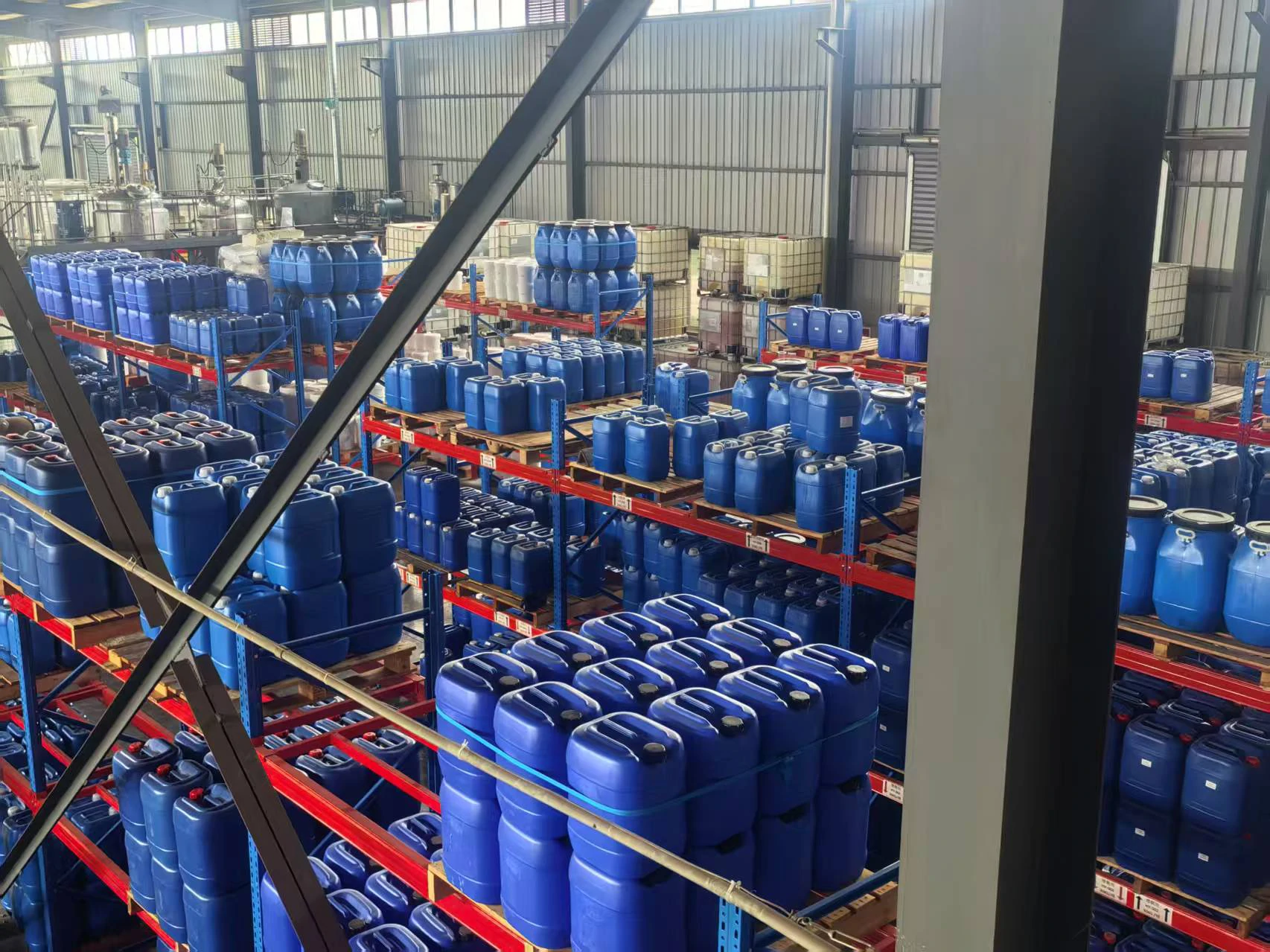 Rows of blue drums stacked on pallets in the PrintBar warehouse, with IBC totes behind Rows of blue drums stacked on pallets in the PrintBar warehouse, with IBC totes behind